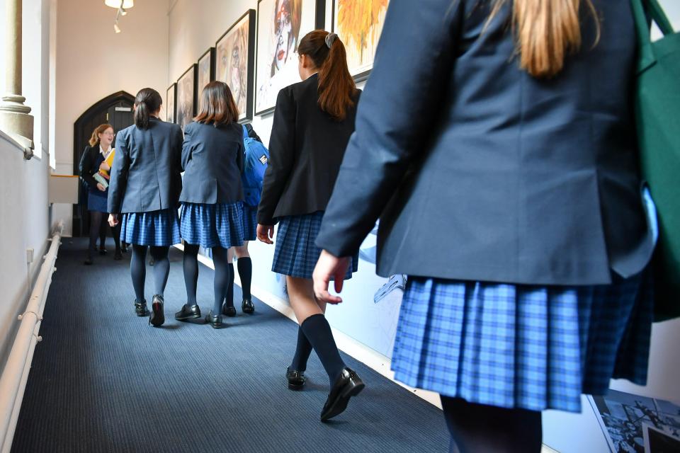 Schoolgirls in uniform walking down a school corridor.