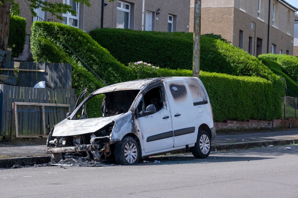 Burnt-out van on a residential street.