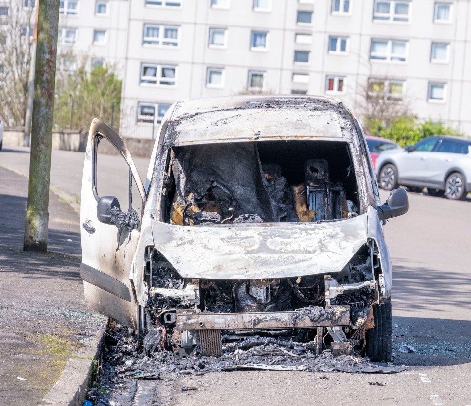 Burnt-out van on a city street.