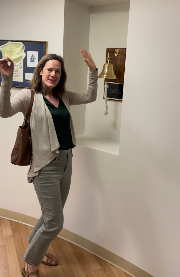 Person ringing a victory bell in an indoor setting, celebrating a personal milestone