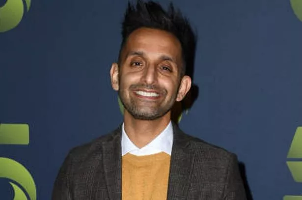 Dr Amir Khan standing in front of a blue backdrop with the Channel 5 logo