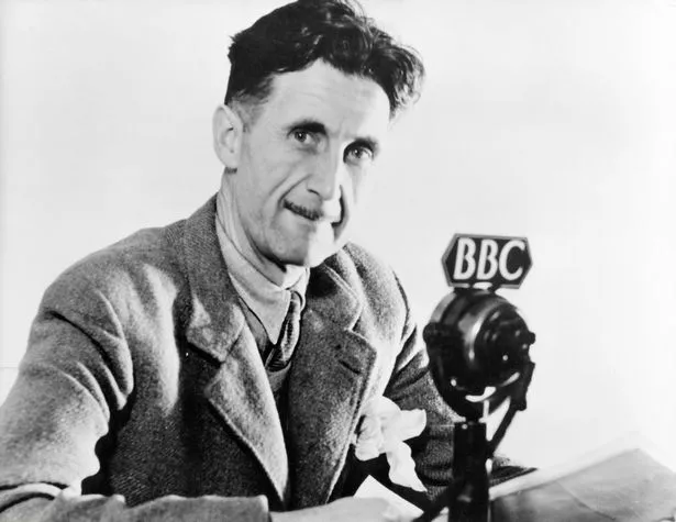 George Orwell posing for a phptograph in front of a BBC microphone