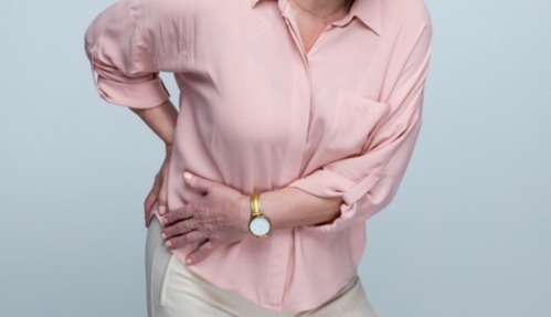Senior woman holding her lower back in pain.