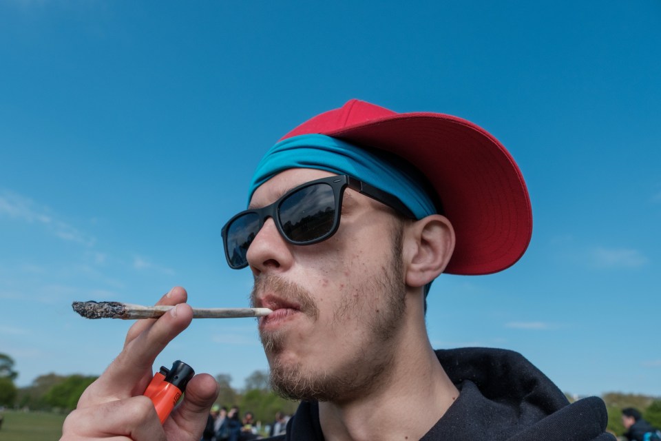 A young man lighting a joint in a park.