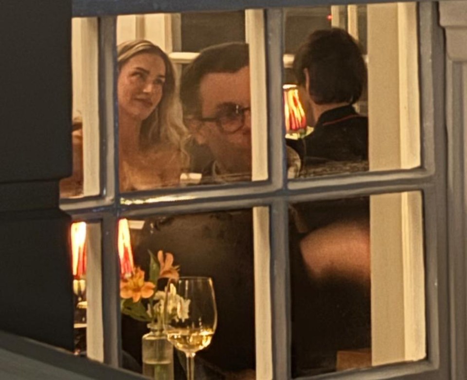 Zara McDermott and Louis Tomlinson seen through a window at a restaurant.