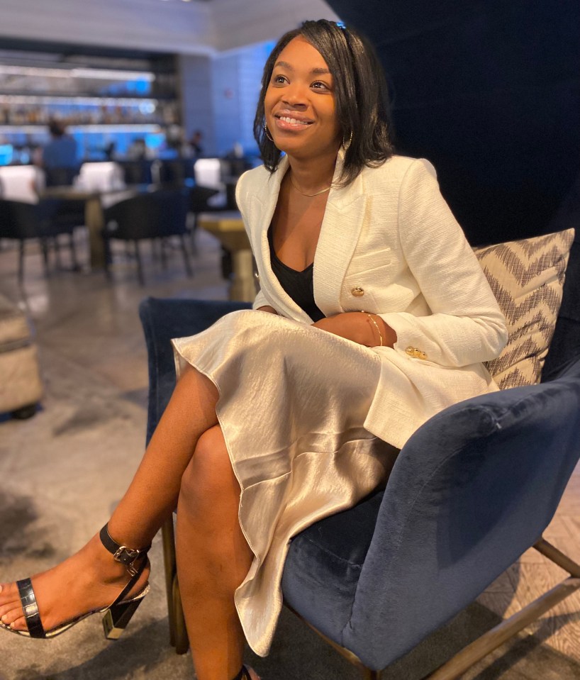 Woman in a white blazer and champagne-colored skirt sitting in a blue chair.