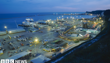 A view of the port of Dover at dusk from the White Cliffs above the port, showing ferries and traffic.