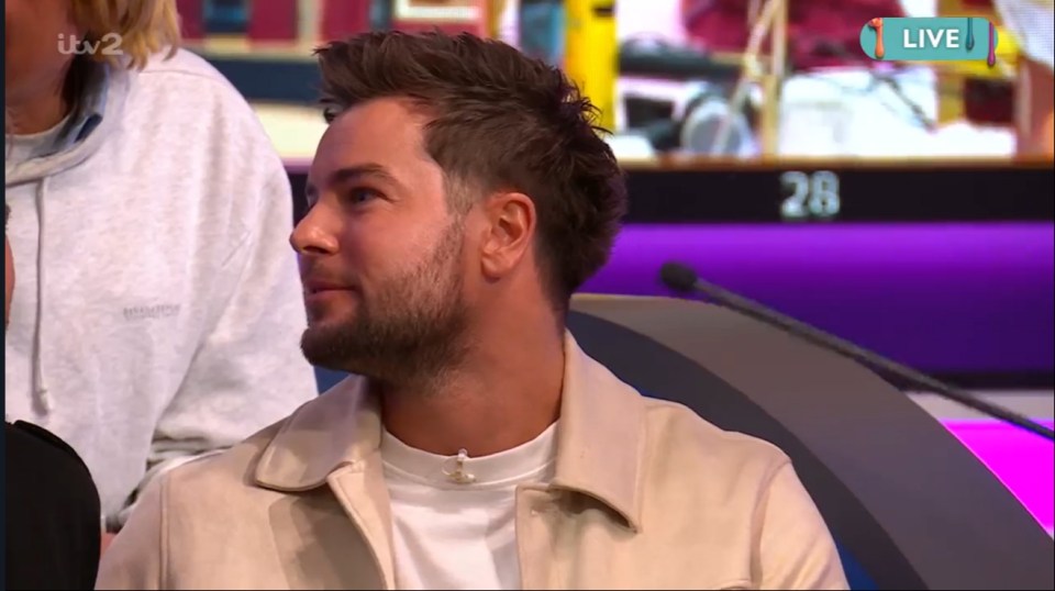 Man with short brown hair in a beige jacket on a game show.