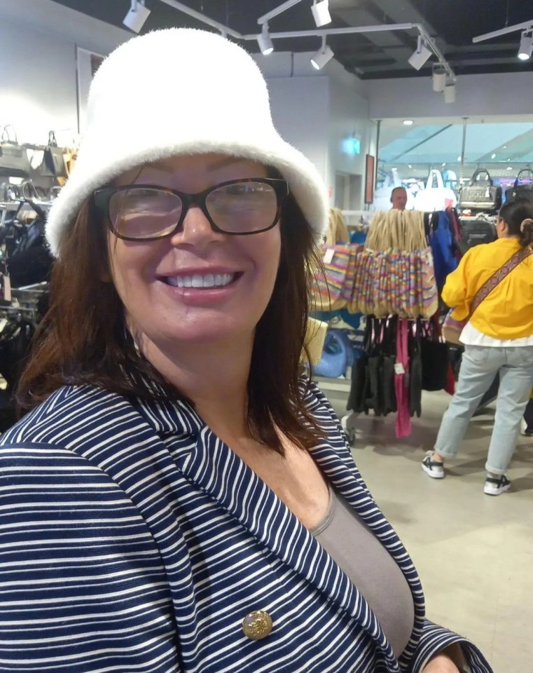 Woman in a white bucket hat and striped blazer smiles for the camera in a store.