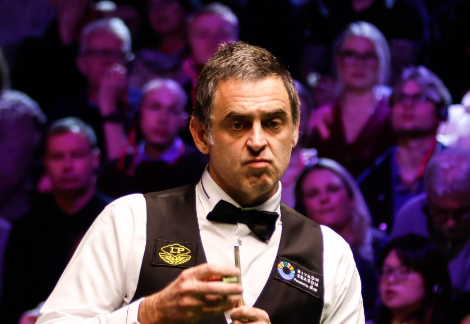 Ronnie O'Sullivan chalking his cue at a snooker match.