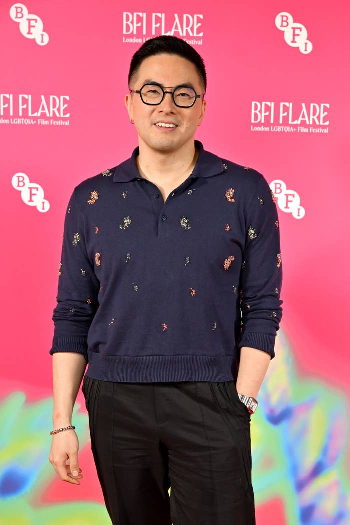 Bowen Yang smiling at the BFI Flare Film Festival, wearing a patterned sweater and glasses