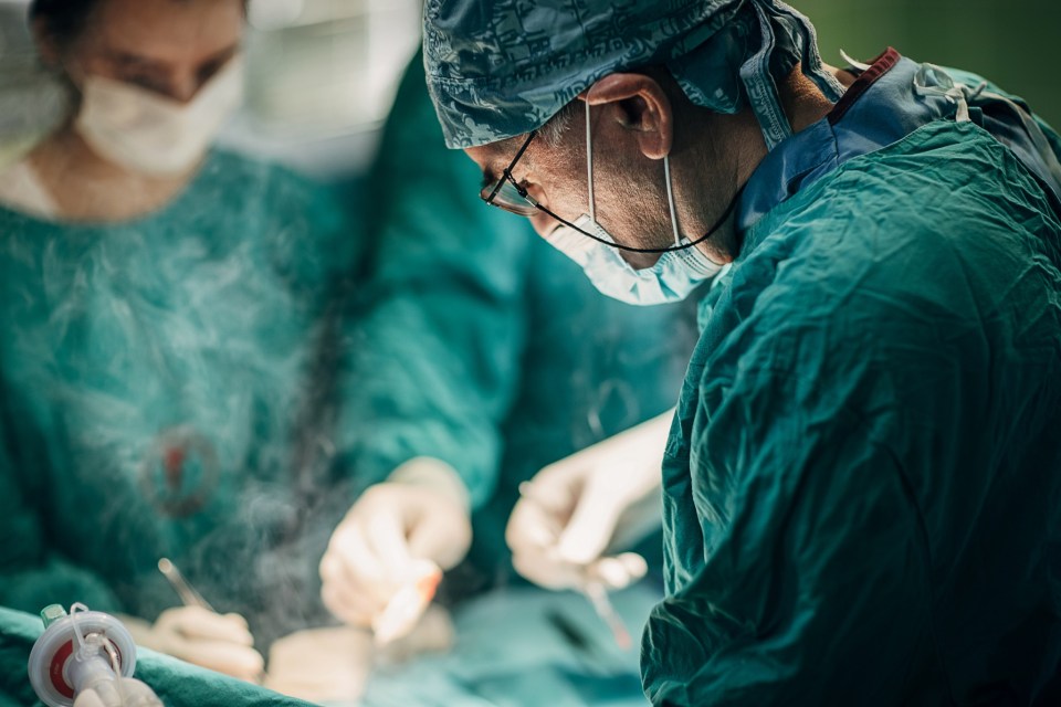 Group of surgeons performing surgery on a patient in operating room. Surgeon is using electrical coagulator during the operation.