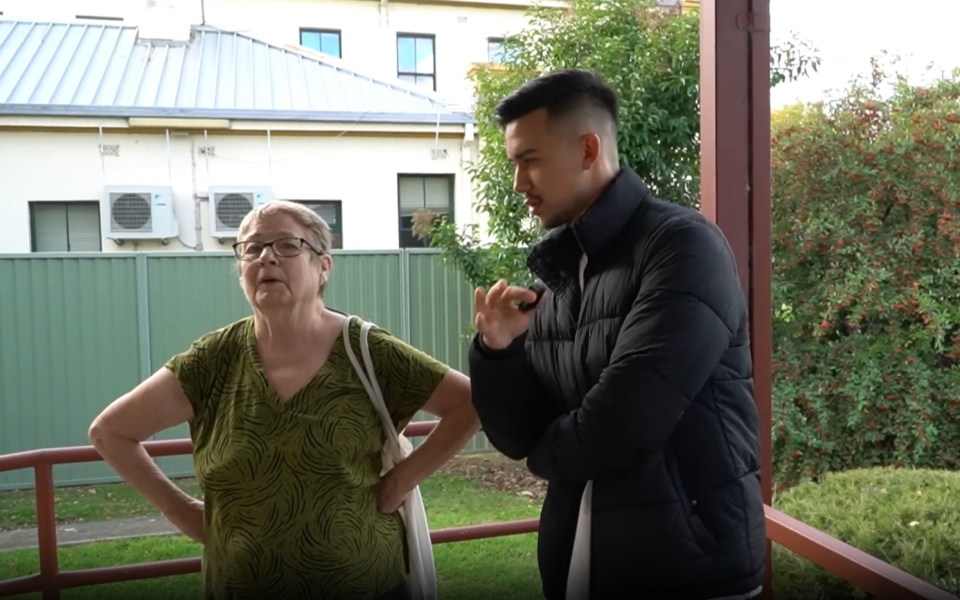 A young man and an older woman talking outdoors.