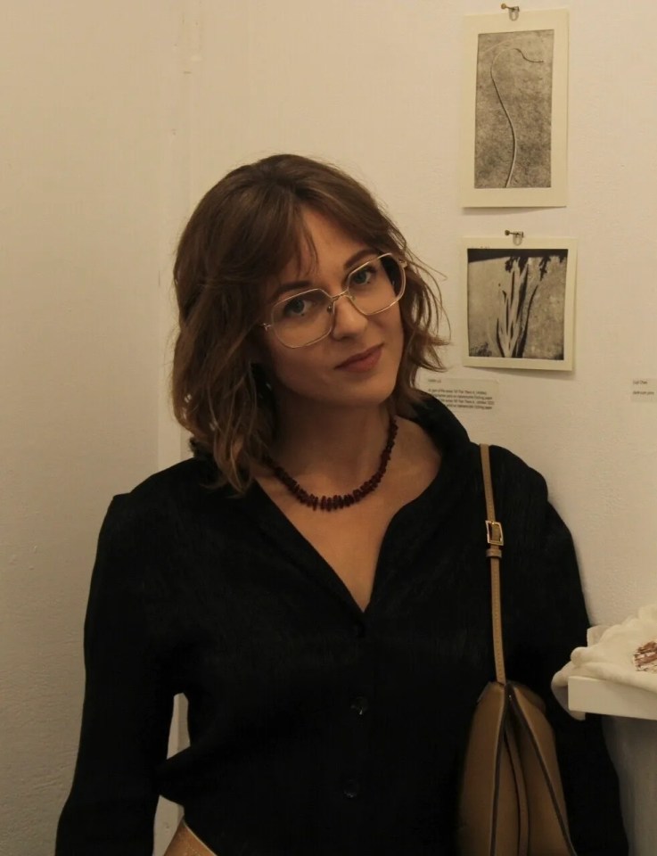 Woman standing near artwork and shells.