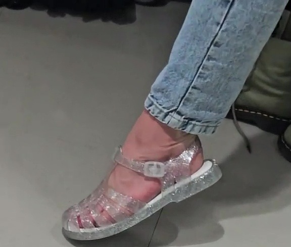 Foot wearing sparkly jelly sandals.