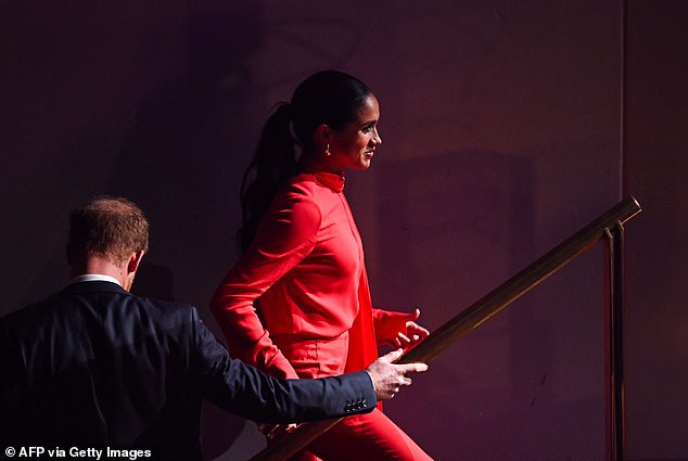 Meghan smiled and held hands with her husband as they made their way through the auditorium ahead of taking to the stage