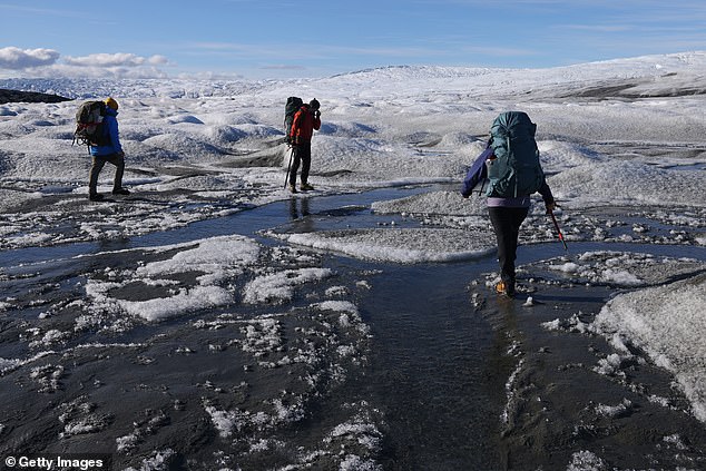 Melting ice and thawing permafrost in the Arctic could release a deadly 'zombie virus' and start the next pandemic, scientists have warned. Pictured: Scientists walk over the thawing Greenland icecap