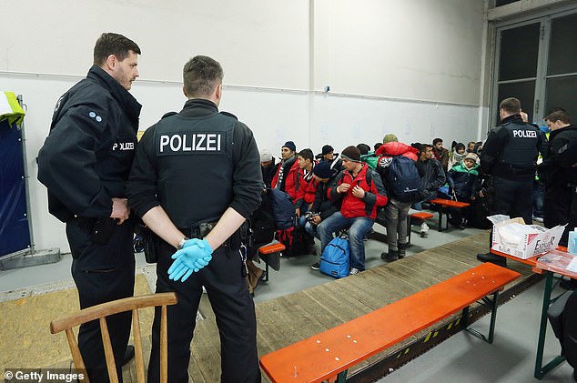 Migrants and refugees arriving from Austria wait to be registered at a processing centre in Germany