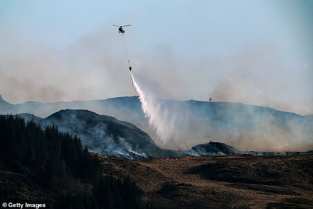 To the rescue: A helicopter douses a wildfire with water on the Isle of Bute