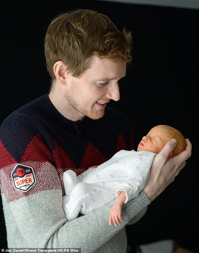 The procedure marked the UK's first successful womb transplant (Pictured: father Angus holds his newborn baby girl)