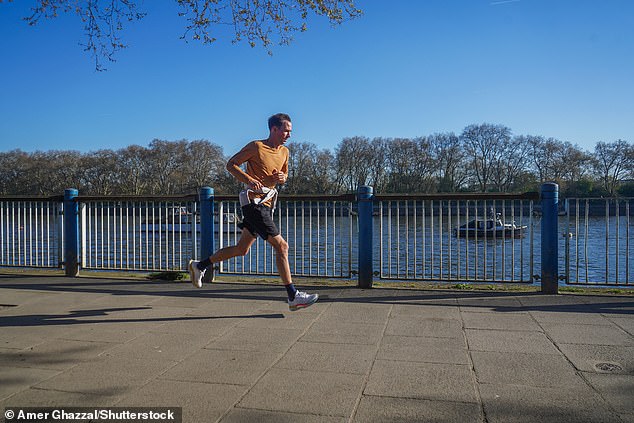A man jogging in the morning sunshine along Putney riverside , south London in the morning sunshine warm weather continues Seasonal Weather, Putney, London, United Kingdom