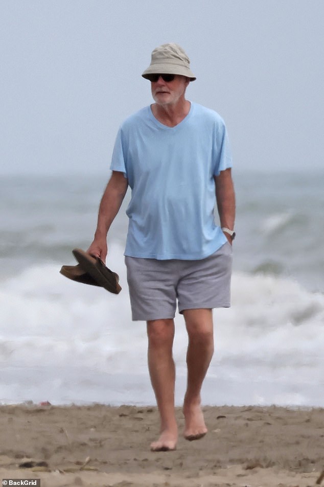 They were also joined by Howard, who sported a light blue T-shirt and grey shorts, strolling barefoot along the beach with his sandals in hand