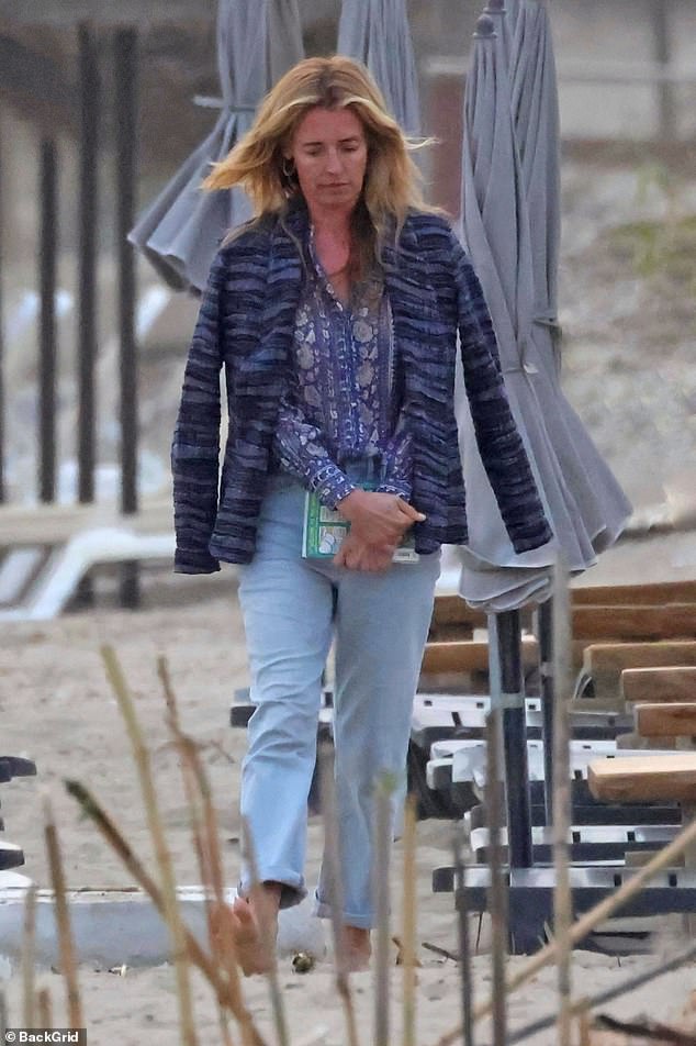 Strolling barefoot on the sandy shore, she was pictured holding a book and completed her laid-back look with gold hoop earrings