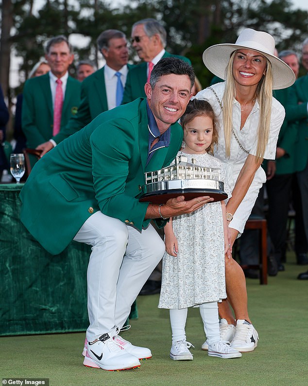 Rory McIlroy poses with daughter Poppy and wife Erica Stoll holding the Masters trophy during the Green Jacket Ceremony after winning the 2025 Masters Tournament at Augusta National Golf Club