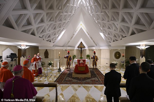 Pope Francis, who died on Easter Monday, pictured lying in a wooden coffin dressed in red, with rosary beads draped across his hands