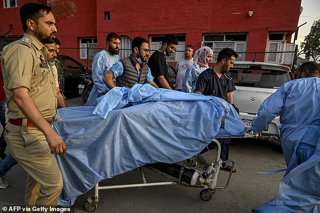 Paramedics and police personnel carry an injured tourist at a hospital in Anantnag, south of Srinagar, on April 22, 2025, following an attack