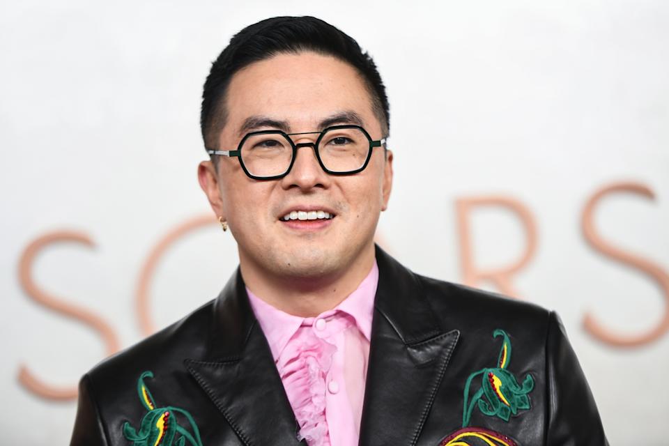 Bowen Yang in a stylish leather jacket with floral embroidery, smiling at an event