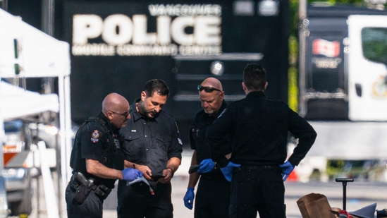 Members of the Vancouver Police forensics team examine a victim's phone while investigating the scene where a vehicle drove into a crowd Saturday killing multiple people at a street festival, in Vancouver, British Columbia, Sunday, April 27, 2025. (The Canadian Press via AP/PTI)(AP04_28_2025_000033B)(AP)