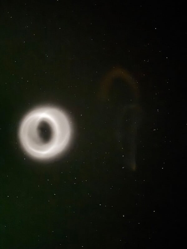 A glowing white circular object and a faint arc shape are visible against a starry night sky. The surrounding area is dark, highlighting the mysterious illuminated forms.