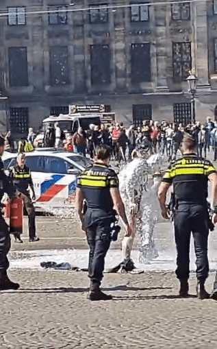 Person covered in foam being attended to by police officers.