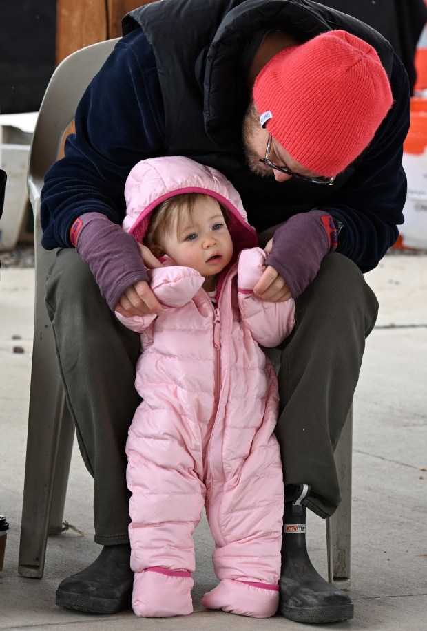 Lily Hamann, 1, and her father, Jeremy, listen to the...