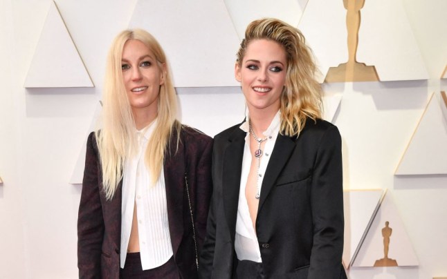 Kristen Stewart with her wife Dylan Meyer, both wearing tuxedos, at the Oscars