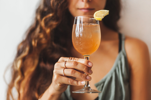 Pretty woman holding glass with tasty and cold kombucha. Healthy refreshment vegan drink