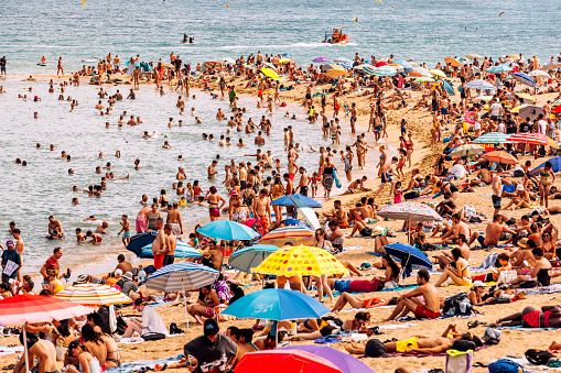 Crowds of people on Barceloneta beach on a hot summer day, Barcelona, Spain