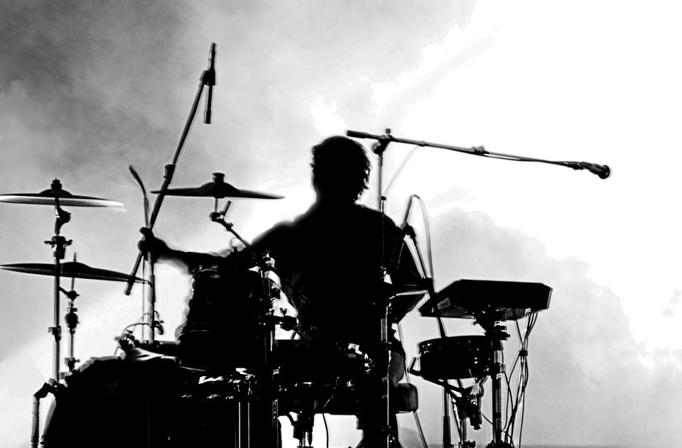 Silhouetted drummer performing on stage.