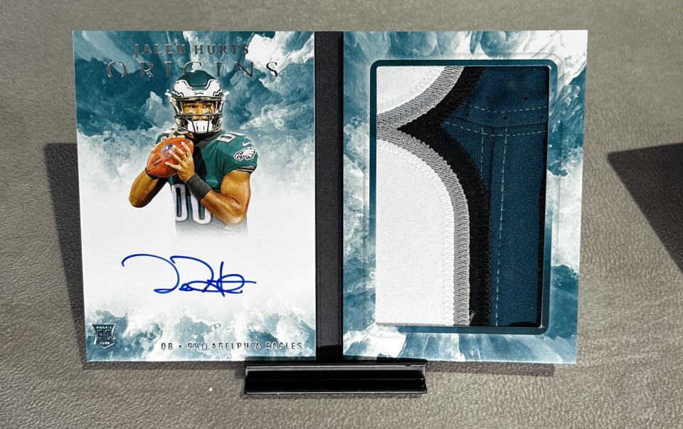 Super Bowl winner Jalen Hurts stars in the stunning central ring with this autographed booklet which also hold a piece of shirt