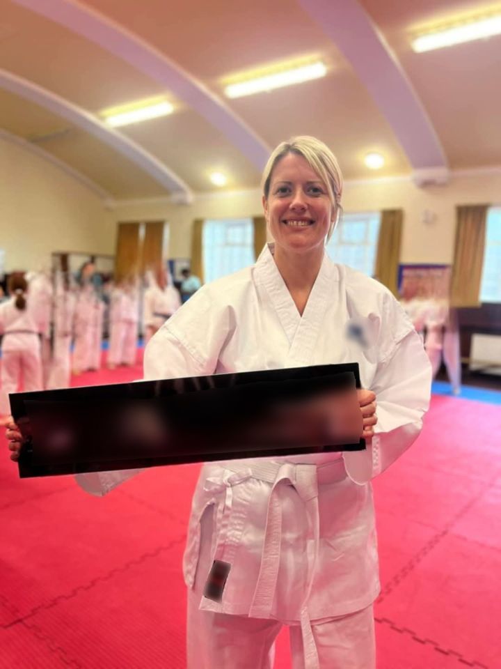 Karate student holding a black rectangular award in a dojo.
