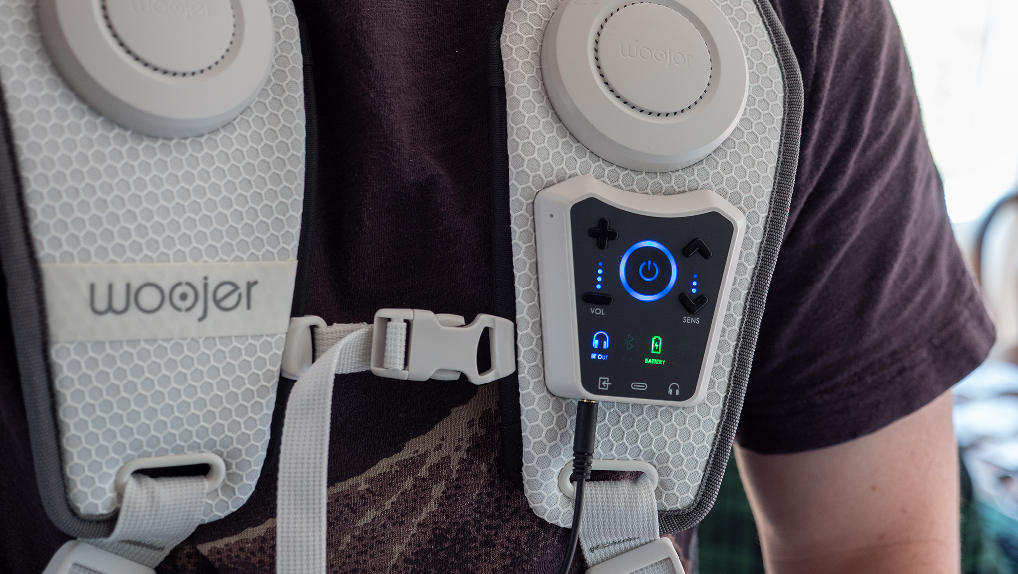 The control panel on the front of a Woojer Haptic Vest 3 with a 3.5mm input cable connected