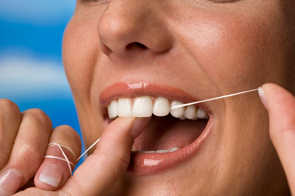 Close-up of a woman flossing her teeth.