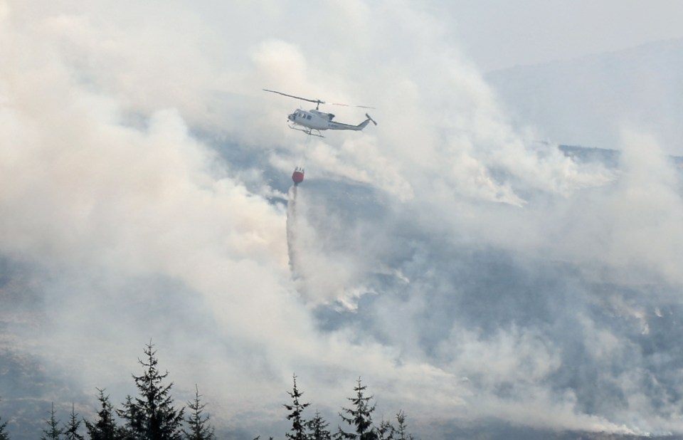 Helicopter dropping water on a wildfire.