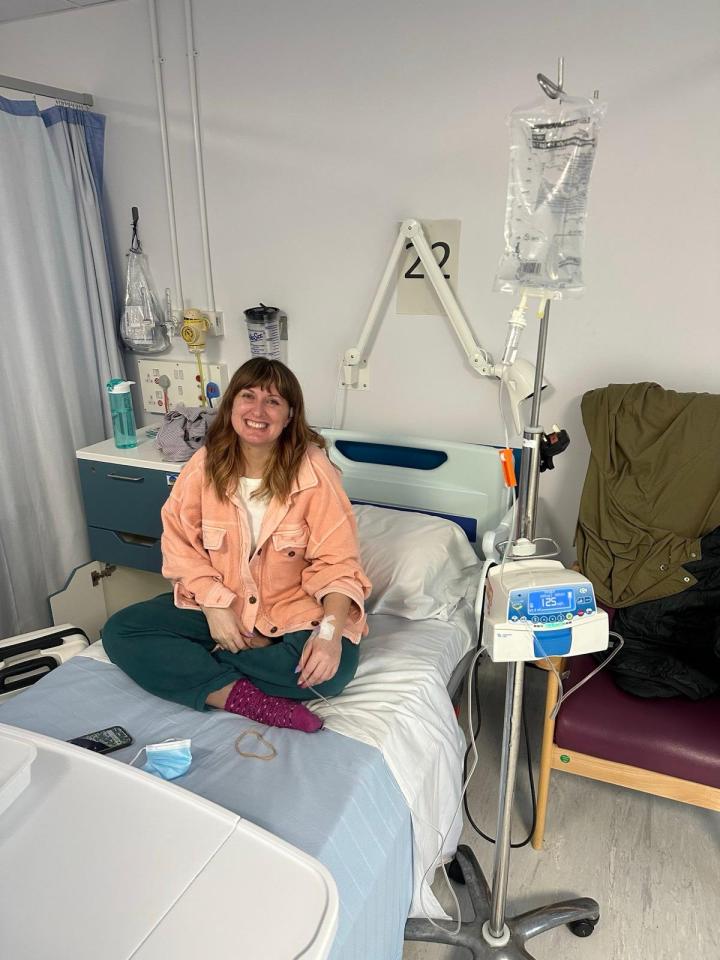 Woman sitting in a hospital bed receiving an IV drip.