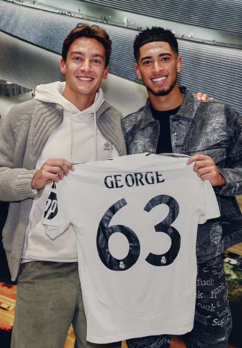 Two men holding up a soccer jersey with the name "GEORGE" and number "63".