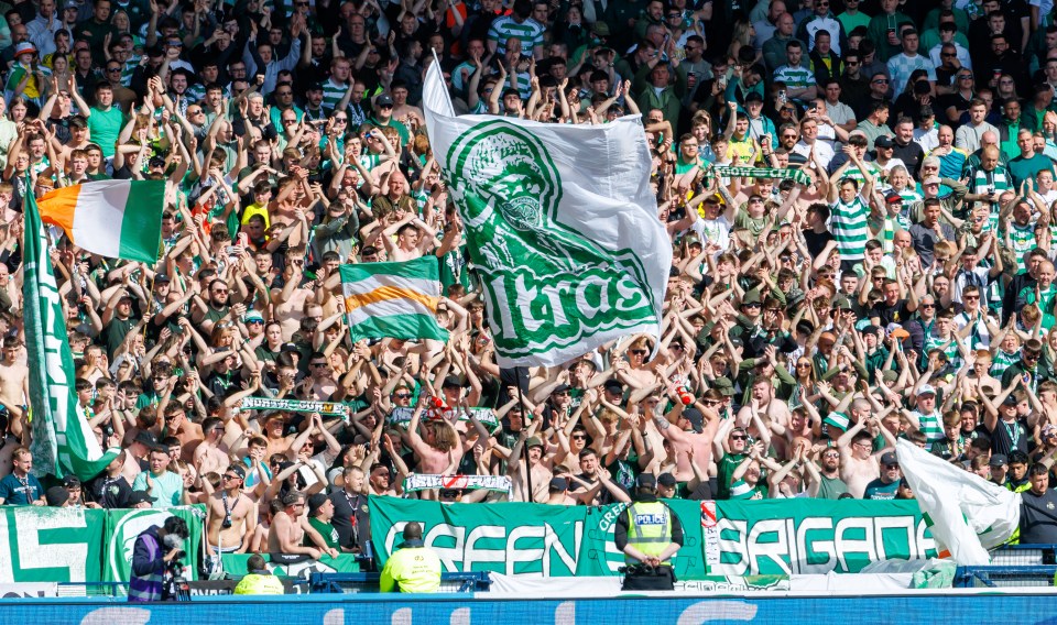 Celtic fans cheering and waving flags at a soccer game.