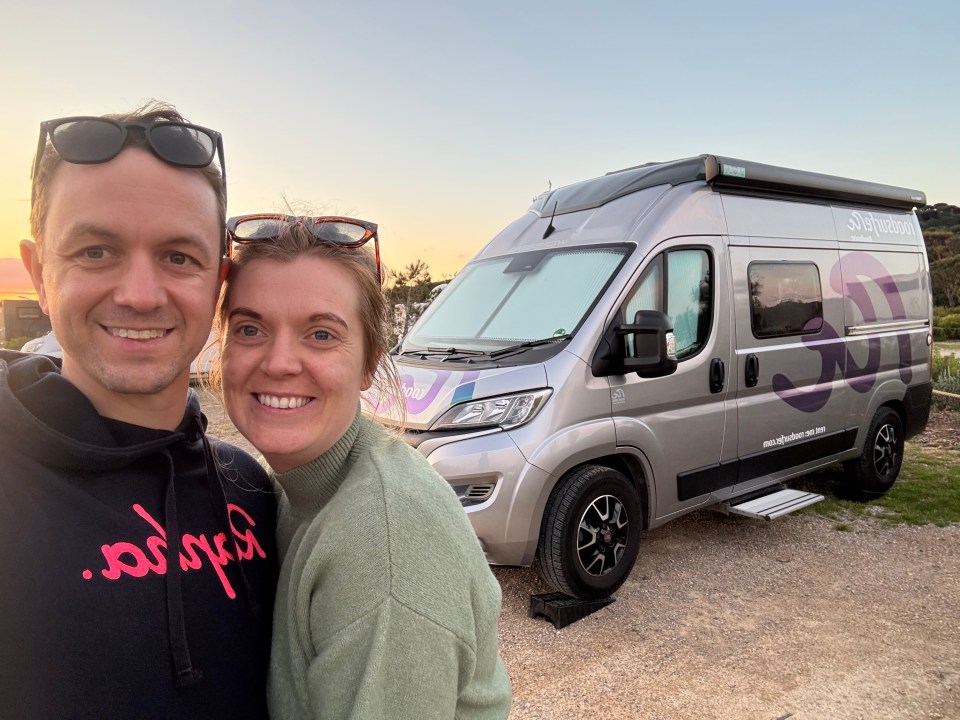 Couple posing for a selfie in front of their campervan.