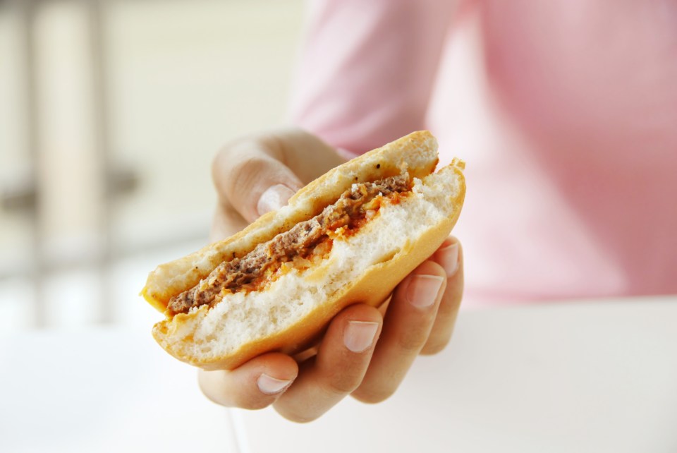 A hand holding a half-eaten hamburger.