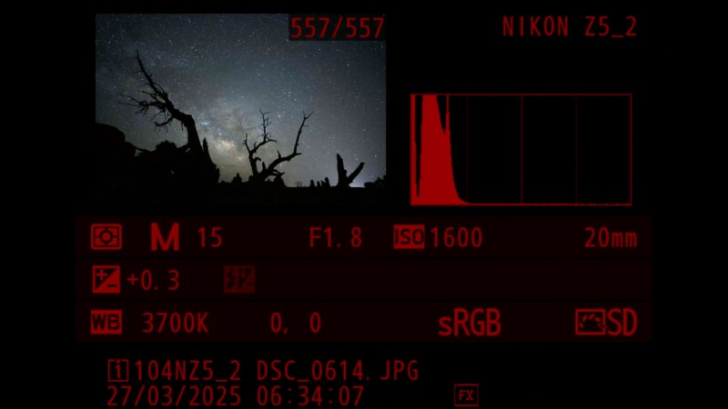 Camera display showing a nighttime landscape photo with silhouetted trees against a starry sky. Settings: M mode, 15s exposure, f/1.8, ISO 1600, 20mm lens, +0.3 exposure compensation, 3700K white balance. Histogram visible.